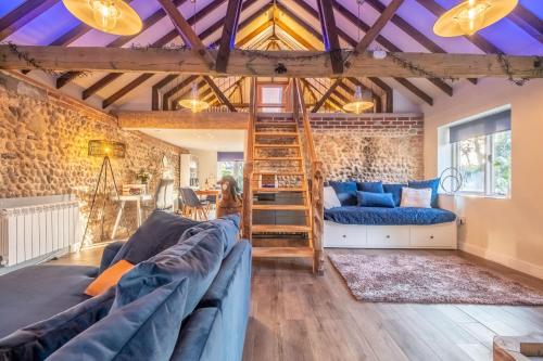 a living room with blue couches and a wooden ceiling at Homestead and Black Cat Barn in Northrepps