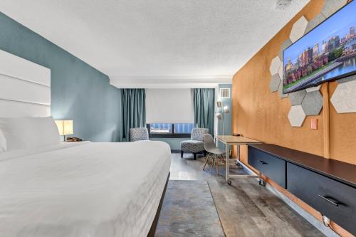a hotel room with a bed and a flat screen tv at Buffalo Airport Hotel in Cheektowaga