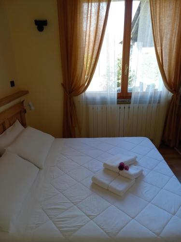 ein Schlafzimmer mit einem weißen Bett mit Handtüchern und einem Fenster in der Unterkunft RESIDENZA BERETTA Como Lake -A- in Orsenigo