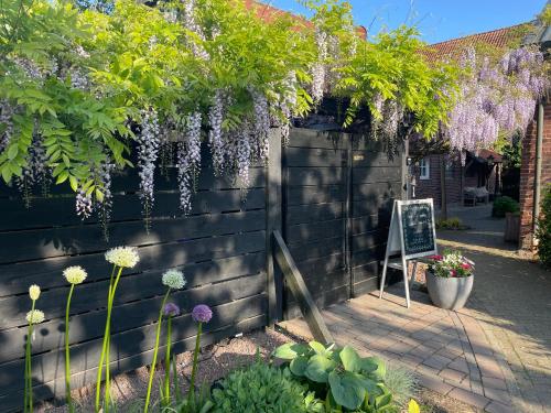 a garden with purple wisterias hanging from a fence at Weberhof - Münster 5 in Münster
