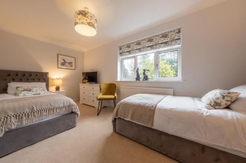 Un dormitorio con dos camas y una ventana. en Harp Garden, en Fakenham