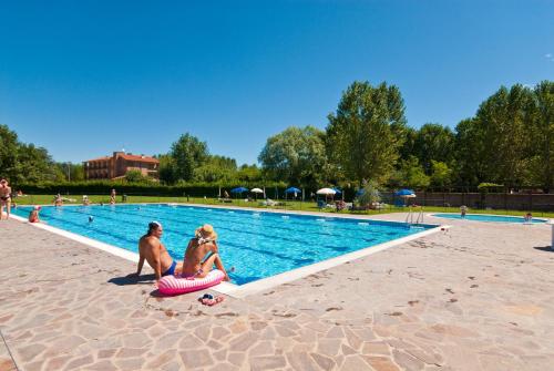a man and a woman sitting next to a swimming pool at Campeggio del Garda in Peschiera del Garda