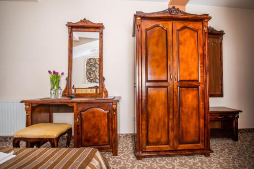 a bedroom with a large wooden cabinet and a mirror at Hotel & Restauracja Gniecki in Hrubieszów