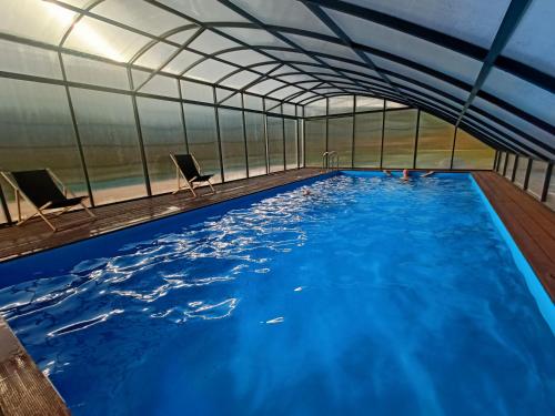a large indoor swimming pool with two chairs in it at Domki na Kaszubach - Chabry i Rumianki - Roztoka, Przywidz - Basen Sauna Jacuzzi KASZUBY in Roztoka