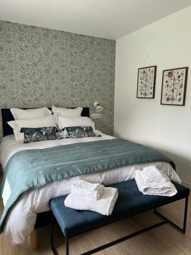 - une chambre avec un grand lit et 2 serviettes sur un banc dans l'établissement La laiterie, à Bouhet