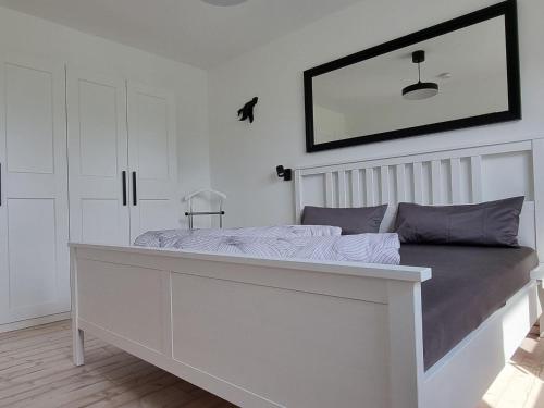 a white bedroom with a bed with a mirror on the wall at Cozy Apartment in Satow Kuhlungsborn and Doberan with garden in Satow