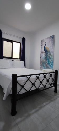 a bedroom with a large bed with a picture on the wall at Casa Jardín Real in Temixco