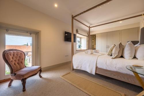 a bedroom with a large bed and a chair at Horse Yard Barn in Warham