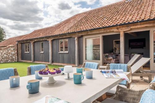 a patio with a table and chairs and a house at Horse Yard Barn in Warham