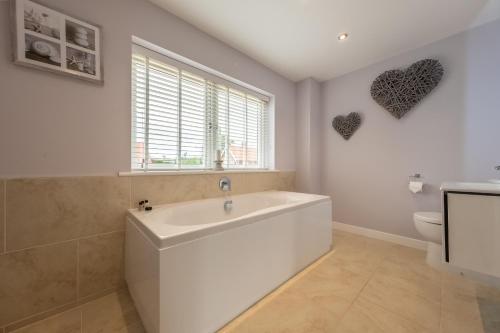 a white bathroom with a tub and a toilet at Field View in Sedgeford