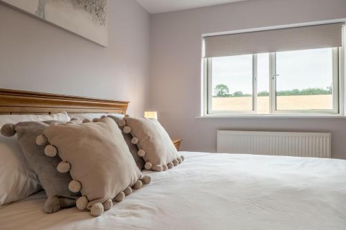 a bedroom with a white bed with pillows and a window at Field View in Sedgeford