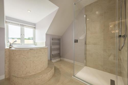a bathroom with a shower and a tub and a sink at Field View in Sedgeford