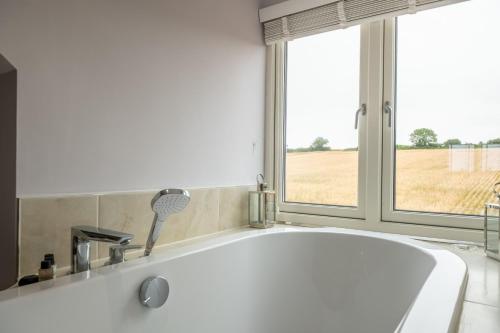 a white bath tub in a bathroom with a window at Field View in Sedgeford