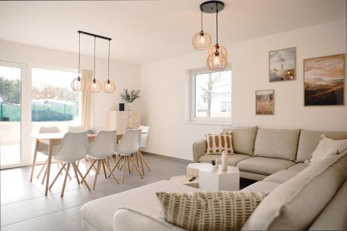 sala de estar con sofá, mesa y sillas en SKAN-PARK Ferienhäuser & Tiny Houses am Bärwalder See 