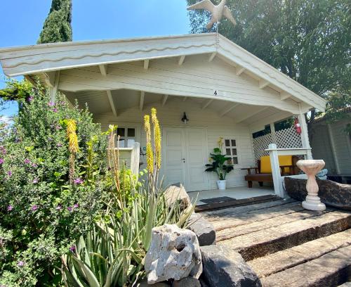 a small white house with a porch and flowers at פינה ברמות - צימרים לנוף הכנרת in Moshav Ramot
