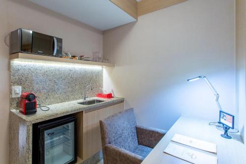 Cette chambre comprend une cuisine avec un évier et un bureau. dans l'établissement CULLINAN HOTEL flat de luxo apartamento 302, à Brasilia