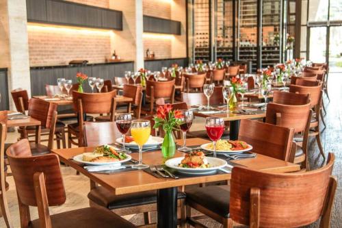 a dining room with tables and chairs with food and wine glasses at CULLINAN HOTEL flat de luxo apartamento 302 in Brasilia