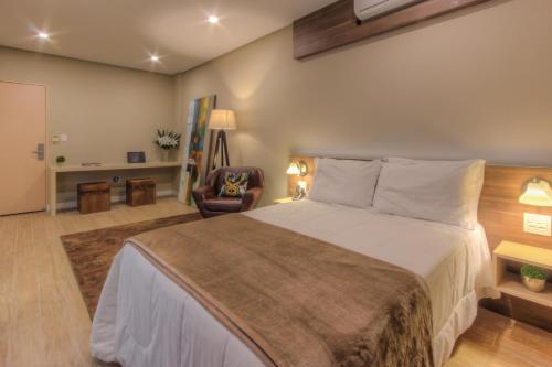 Tri Hotel Lajeado في لاجيدو: غرفة نوم بسرير كبير وكرسي