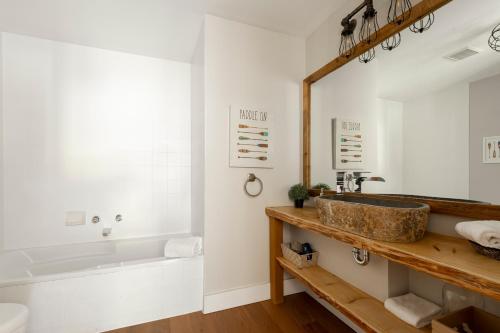 ein Badezimmer mit einem Waschbecken, einer Badewanne und einem Spiegel in der Unterkunft The Outlook over Lac -Tremblant by Instant Suites in Mont-Tremblant