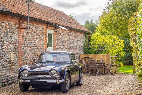 an old car parked in front of a brick house at The Stables in North Walsham