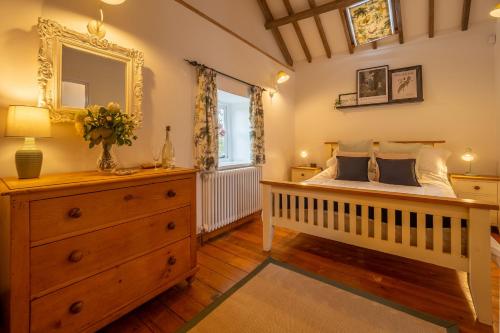 a bedroom with a crib and a dresser and a mirror at The Stables in North Walsham