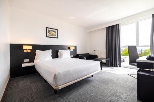 a hotel room with a bed and a living room at Globales Post Hotel & Wellness in Herstal
