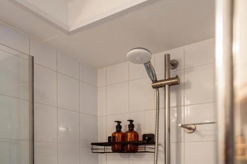 a shower in a bathroom with bottles on a shelf at B&B Hendricus in Hoofddorp