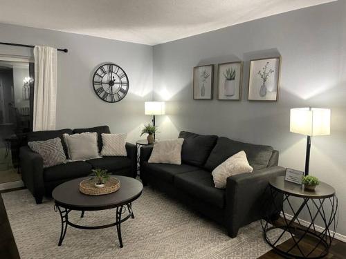 a living room with a black couch and two tables at Luxury Modern Condo by the Lake - Succulent Way in Branson