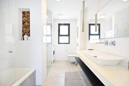 a white bathroom with two sinks and a toilet at Luxury Penthouse in Netanya in Netanya