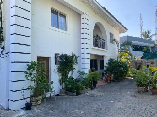 Un edificio blanco con plantas delante. en Studio C, (Studio Apartment) Hillside Gardens, en Lagos