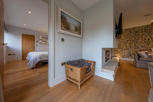 ein Schlafzimmer mit einem Bett und ein Wohnzimmer mit einem Kamin in der Unterkunft 5 Manor Farm Barns in Brancaster