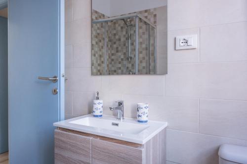 a white bathroom with a sink and a mirror at Appartamento con parcheggio e Aria Condizionata in Lerici