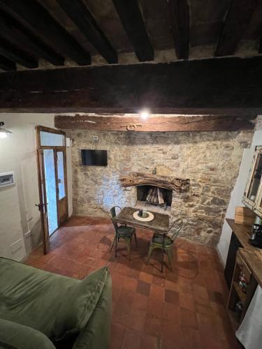 a living room with a table and a stone fireplace at La casa del Teatro in Campiglia dʼOrcia