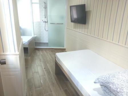a bathroom with a bed and a tv on the wall at K & B Hostel in Hong Kong