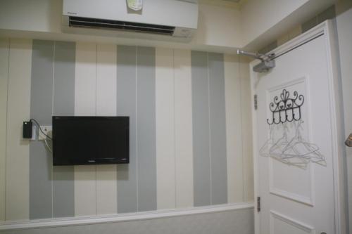 a room with a tv on a striped wall at K & B Hostel in Hong Kong