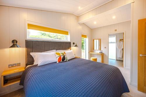 ein Schlafzimmer mit einem Bett mit blauer Decke und einem Fenster in der Unterkunft Ingol Lodge 2 in Ingoldisthorpe