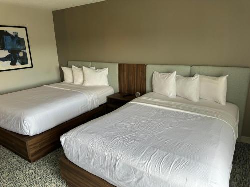 a hotel room with two beds with white sheets at Wingate by Wyndham Hattiesburg in Hattiesburg