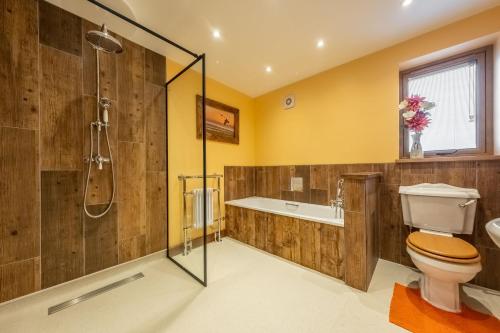 a bathroom with a shower and a toilet and a tub at Bootlegger's Barn in Heacham