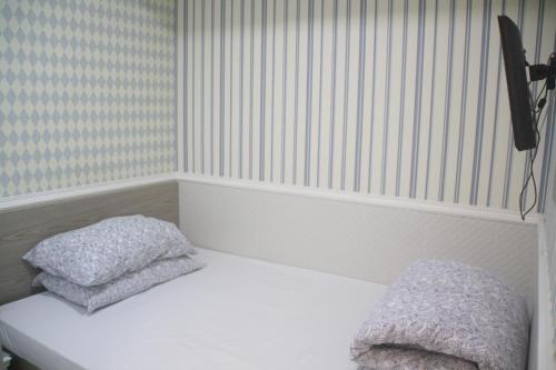 a bed with two pillows on it in a room at K & B Hostel in Hong Kong