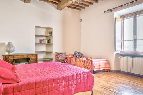 1 dormitorio con cama roja, mesa y sillas en Casale - I Tre Cipressi, en Arezzo