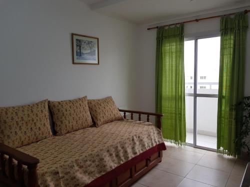 1 dormitorio con sofá y ventana con cortinas verdes en Departamento Céntrico en Salta
