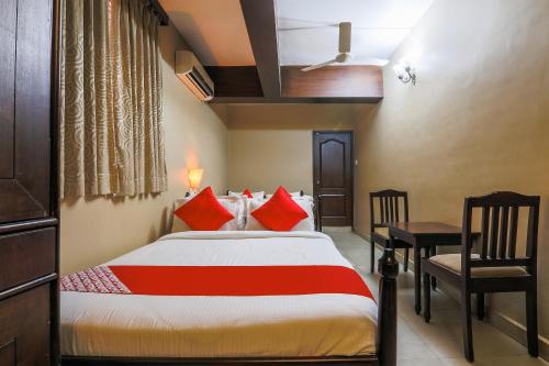 a bedroom with a bed with red pillows and a desk at Kams Coco De Parra in Baga