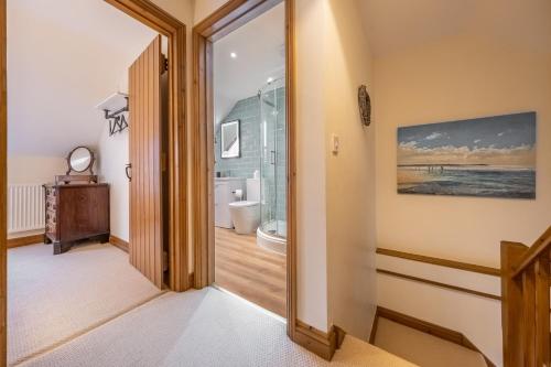 um corredor com uma porta que leva a uma casa de banho em Sandpiper Lodge em Little Walsingham