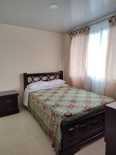 a bedroom with a bed with a quilt and a window at Lugar acogedor, Ideal para estar en familia. in Santa Rosa de Cabal