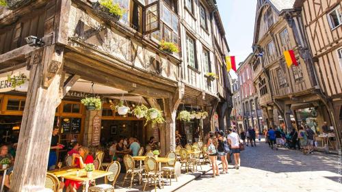 une rue avec des tables et des chaises et des personnes assises aux tables dans l'établissement Chambre chez l'Habitant La Rance, à Plouër-sur-Rance