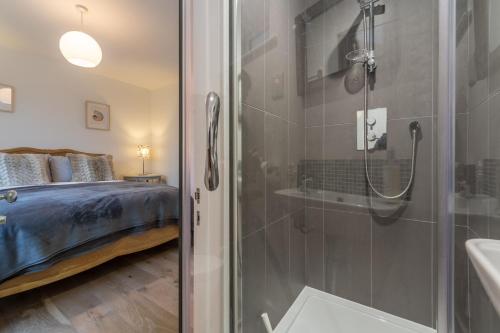 een badkamer met een douche en een slaapkamer met een bed bij Marsh Tide 4 in Brancaster