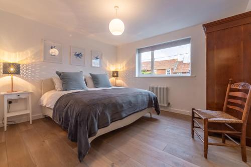 a bedroom with a bed and a window and a chair at Marsh Tide 4 in Brancaster