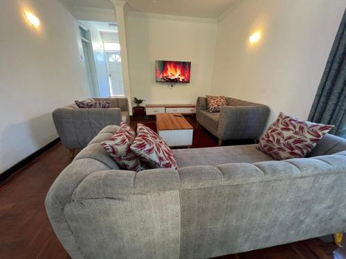a living room with a couch with pillows on it at El Tessa garden/serviced apartment in Kisumu