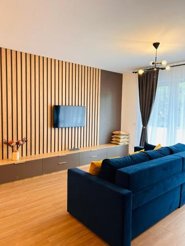 uma sala de estar com um sofá azul e uma televisão em Brand new, feel at home residence em Timisoara