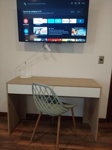 a desk with a computer monitor on a wall with a chair at Hotel Boutique Quinta Camacho in Bogotá